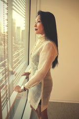 Sideview of Anna in her custom hand embroidered piña silk Barong Tagalog. Anna looks out the window and holds onto a white handrail with both hands.
