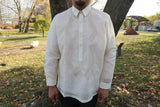Product shot of the hand embroidered jusi John-T Barong Tagalog. John-T stands in front of a tree with grass, sculptures and a park behind him