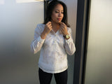 Krizia stands next to panels of frosted glass in her hand embroidered jusi Barong Tagalog. She also wears a wrsit watch and tight black pants. Krizia is holding each side of her barong's collar with her hands and she looks down and away