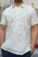 Product photo of the short sleeve hand embroidered jusi Barong Tagalog. Matt also wears a chamisa de chino underneath his barong, blue pants and a watch on his left wrist. Matt stands in front of the Los Angeles Public Library