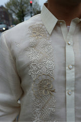 Closeup of the right side of the calado hand embrodery on the piña silk Ricky Barong Tagalog. There is a car, building, tree and traffic light in the background.
