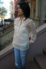 Robin stands in front of a Harlem porch in her hand embroidered piña silk Barong Tagalog, white tank top underneath her barong, and blue jeans. Robin stands at angle with her hands behind her back and legs crossed