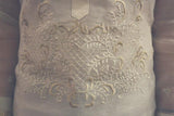 Closeup photo of the bottom of the calado hand embroidery on the piña silk Roe Barong Tagalog. Roe wears a white tank top underneath her barong.