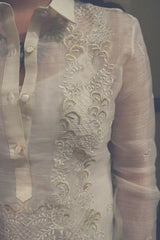 Closeup photo of the right side of the calado hand embroidery on the piña silk Roe Barong Tagalog. Roe wears a white tank top and necklace underneath her barong.
