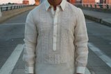 Product picture of the hand embroidered piña silk RonRiz Barong Tagalog. Ronnie wears a chamisa de chino underneath his barong. He stands in the middle of the street at the Roebling Suspension bridge. The bridge's rails and the buildings on the other side of the bridge are in the background