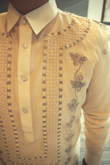 Closeup on the upper right side of the embroidery on the jusi Tonilyn Barong Tagalog. There is a grey and white wall and window in the background