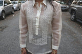 Product shot of the hand embroidered piña silk Jenny Barong Tagalog. Jenny wears a beige tank top underneath her barong, grey skirt and gold bracelets. Jenny stands in the middle of the street with cars on both sides of the street