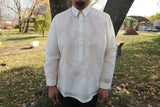 Product shot of the hand embroidered jusi John-T Barong Tagalog. John-T stands in front of a tree with grass, sculptures and a park behind him 