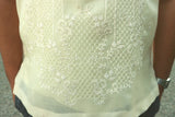 Closeup photo of the bottom of the calado hand embroidery on the cocoon Marc Barong Tagalog. Marc's arms are visible. Marc wears a silver watch on his left wrist. He wears grey pants