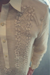 Closeup of the calado hand embroidery on the left side of the piña silk Mark Barong Tagalog. The center button placket, left side of the pointed collar and the left arm and sleeve can be seen