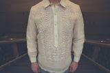 Product photo of the hand embroidered piña silk Mark Barong Tagalog. Mark stands at the top of a stairwell. There are bannisters on both sides and light brown marble walls in the background 