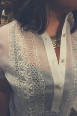 Closeup on the calado hand embroidery on the upper right chest and shoulder side of the cocoon Natalia Barong Tagalog. Natalia wears a black tank top and patterned gold necklace underneath her barong.  