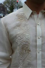 Closeup of the right side of the calado hand embrodery on the piña silk Ricky Barong Tagalog. There is a car, building, tree and traffic light in the background.  