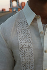 Closeup of the calado hand embroidery on the upper left side of the piña silk RonRiz Barong Tagalog. Ronnie wears a chamisa de chino underneath his barong. The Roebling suspension bridge is in the background