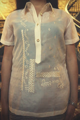 Product shot of the jusi Ryann Barong Tagalog. Ryan wears a tank top underheath her barong, grey skirt and silver watch on her left wrist. She stands in front of a staicase in DC Union Station