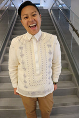 Tonilyn stands at the bottom of a grey stairwell. Tonilyn wears a jusi Barong Tagalog, a chamisa de chino underneath the barong, light brown khaki pants and a beaded bracelet. Tonilyn's hands are in the pockets and Tonilyn is smiling with mouth open